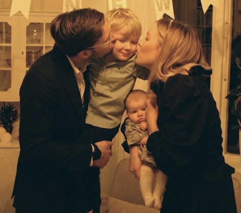 Lovisa och Mattias pussar sin son på kinden medan Lovisa håller en bebis