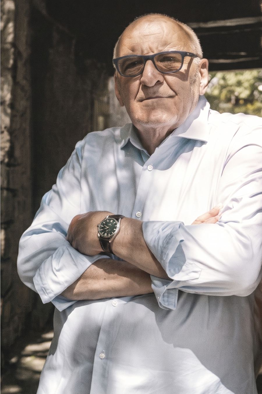 Giorgio med armarna i kors i skuggan under en pergola